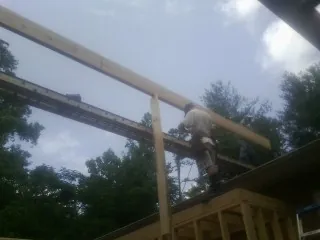 Carpenter setting a ridge beam over a new addition frame — Ice Dam Removal by Roofing Brothers in Lakota