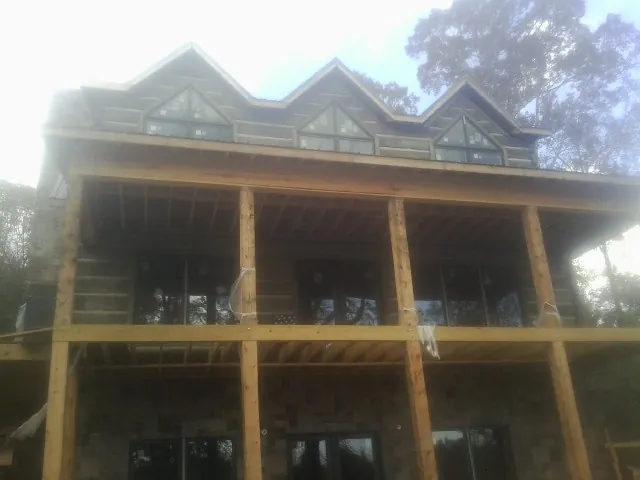 Dormers and porch framing on a large log home under construction — Roof Coating work by our crew in Lakota