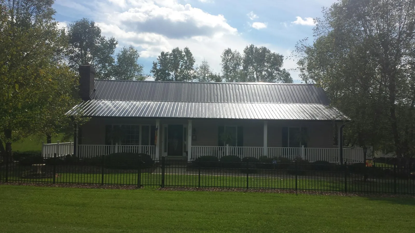 Gray metal roof on a brick ranch with a full width front porch — Gutter Guard Installation work by our crew in Lakota