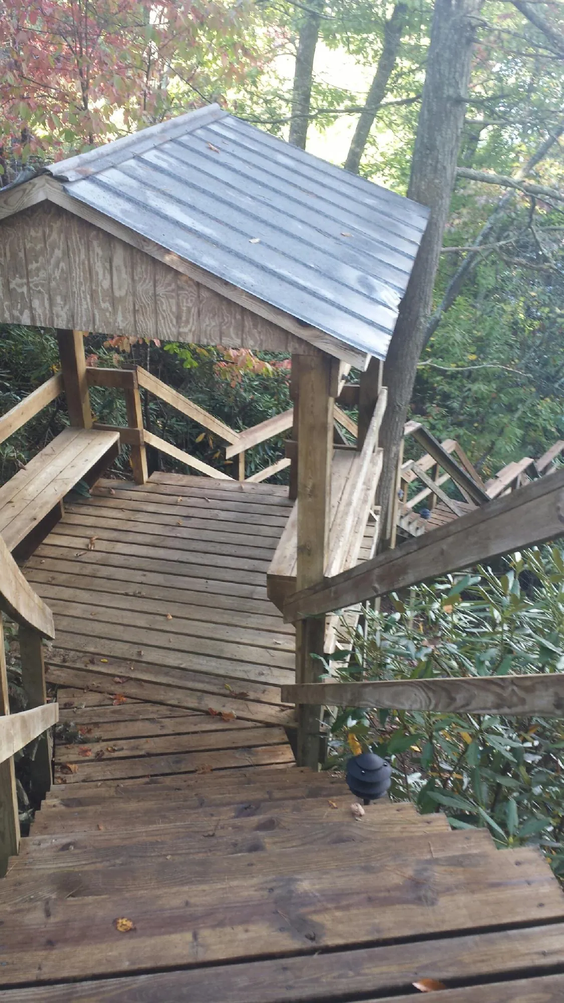 Metal roofed shelter over wooden steps on a wooded walkway — Skylight Repair & Installation work by our crew in Lakota