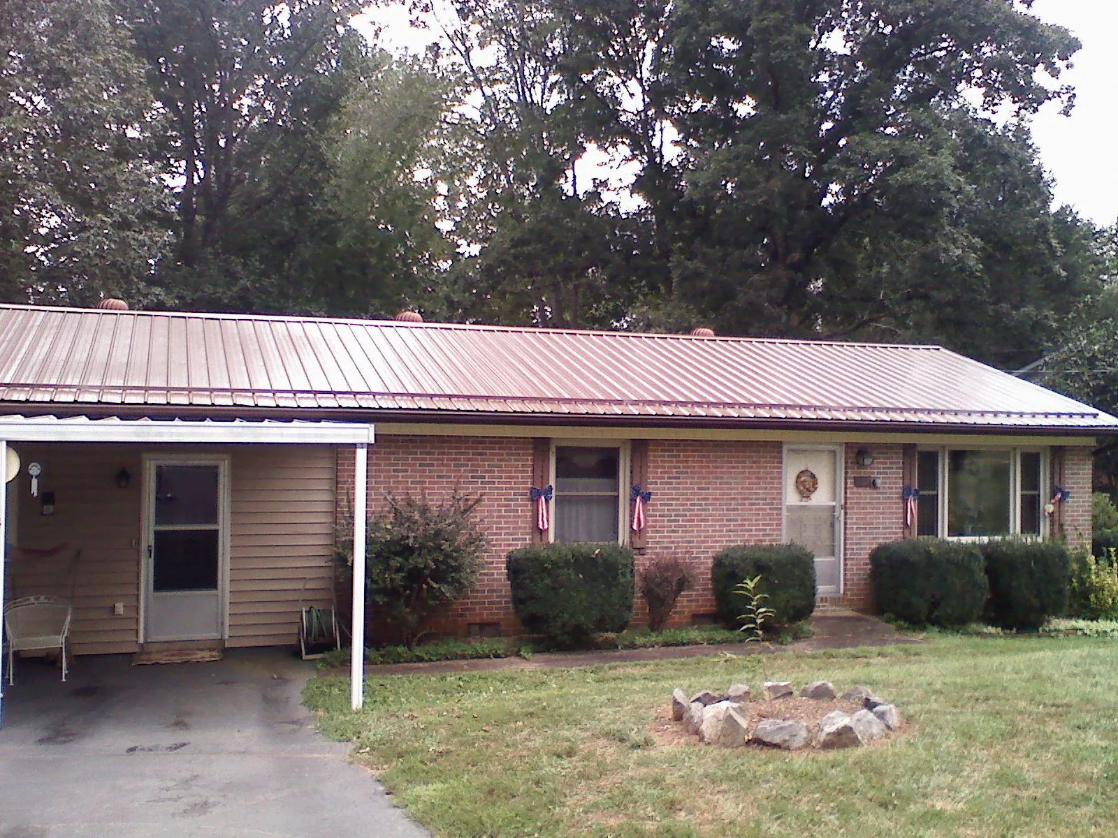Bronze metal roof and carport on a brick ranch home — Roof Repair work by our crew in Lakota