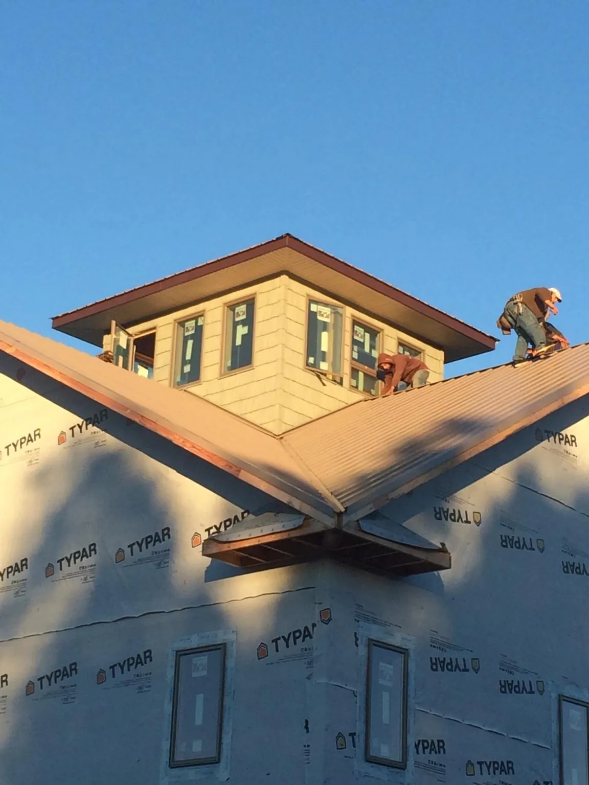 Roofers working around a rooftop cupola on a new metal roof at sunset — Roof Waterproofing in Lakota by Roofing Brothers